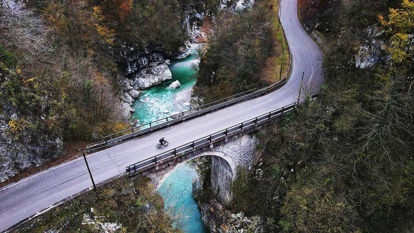 Cyclist alone on a bridge, with beautiful rives flowing under.